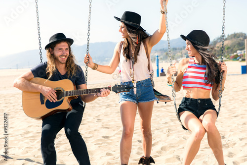 Millennial hipster trendy group of friends on swing set guitar musician fashion leisure casual