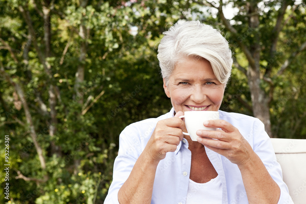 Portrait of smiling mature woman outdoors holding cup Portrait of smiling mature woman outdoors holding cup