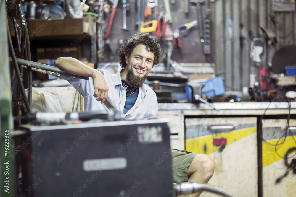Smiling young man with chin beard in alternative technical room Smiling young man with chin beard in alternative technical room