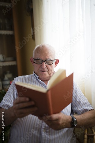 Portrait of senior man reading a book at home photo