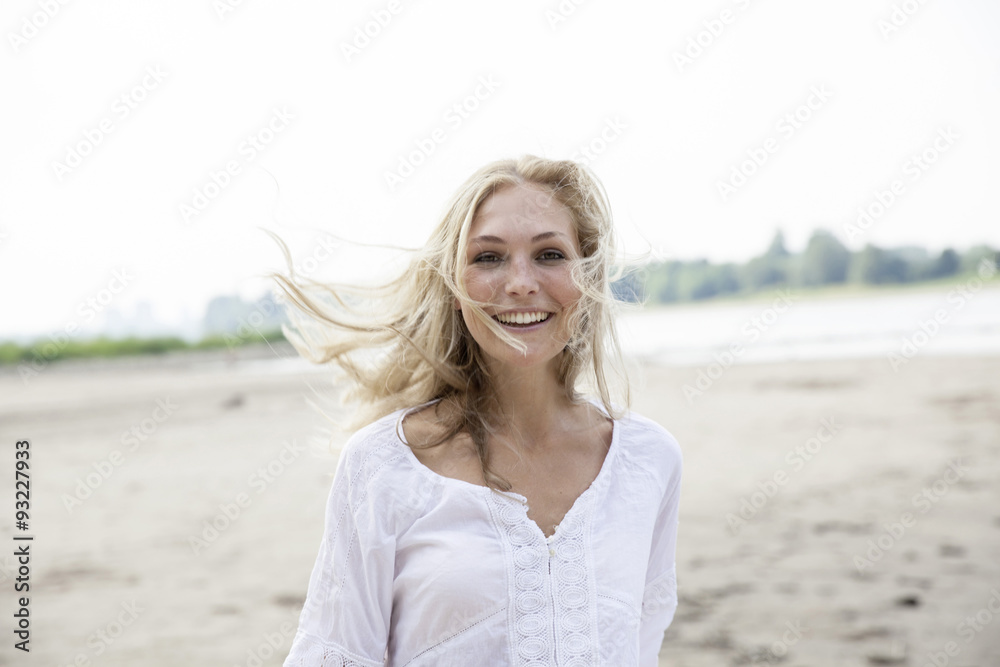 Portrait of smiling blond woman with blowing hat on a beach Portrait of smiling blond woman with blowing hat on a beach