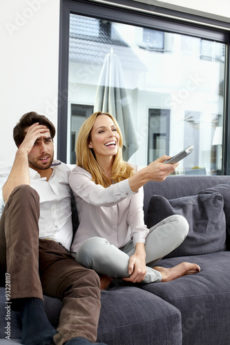 Couple sitting together on couch watching TV show
