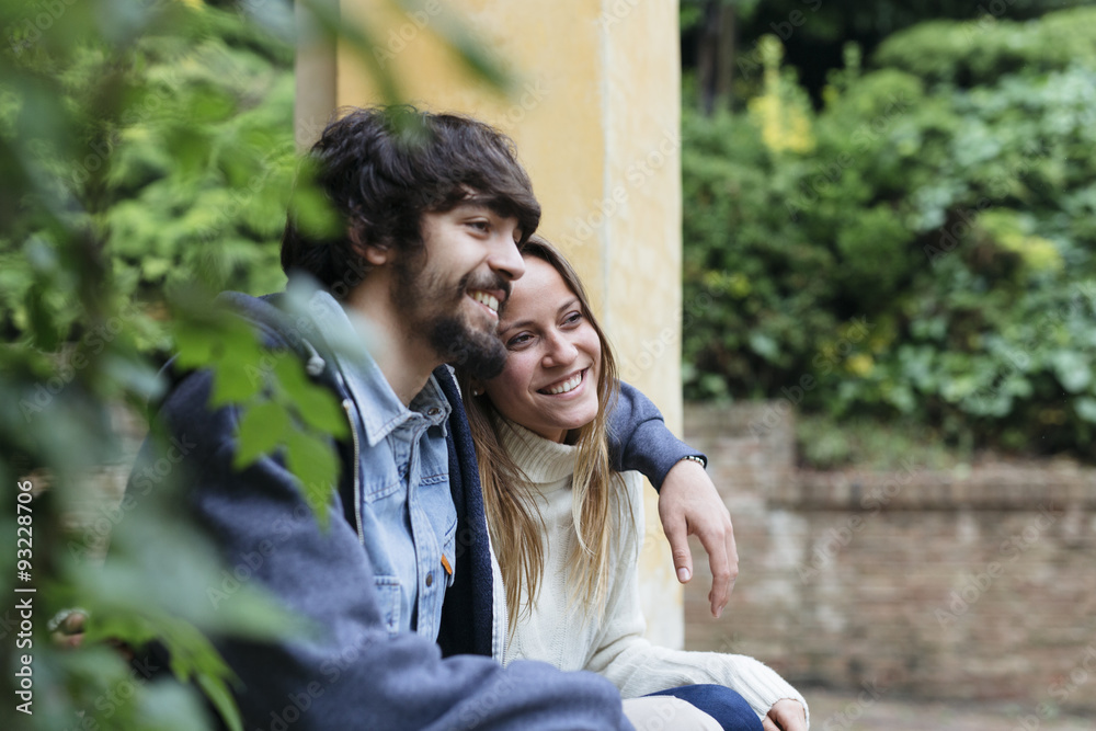 Happy young couple sitting arm in arm having a rest Happy young couple sitting arm in arm having a rest