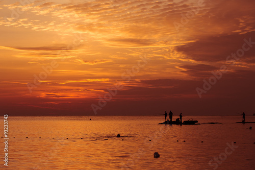 Fototapeta Naklejka Na Ścianę i Meble -  Ocean landscape at sunset. Silhouettes of fishermen.
