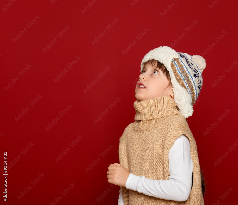 christmas concept - girl in hat and sweater on red background look up