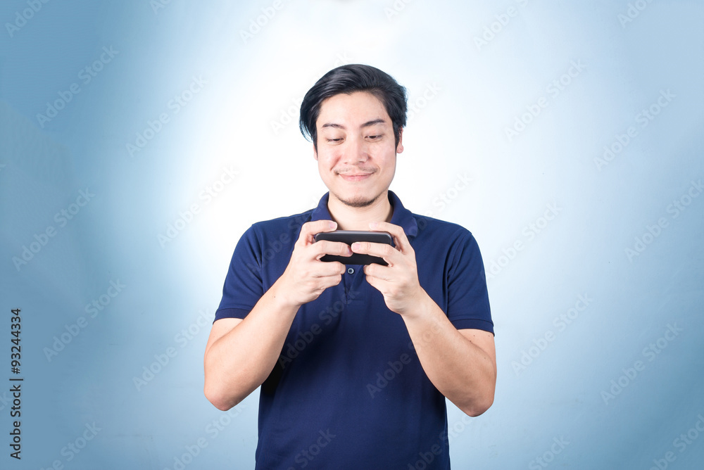 Asian guy with mobile phone in hand, on blue background Asian guy with mobile phone in hand, on blue background