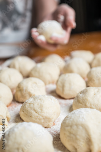 Small balls of fresh homemade dough on floured wooden board