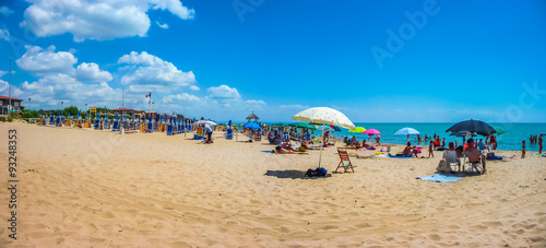 Beautiful vacation beach with beach chairs and sun shades on a sunny day at Lido di Metaponto, Basilicata, Italy photo