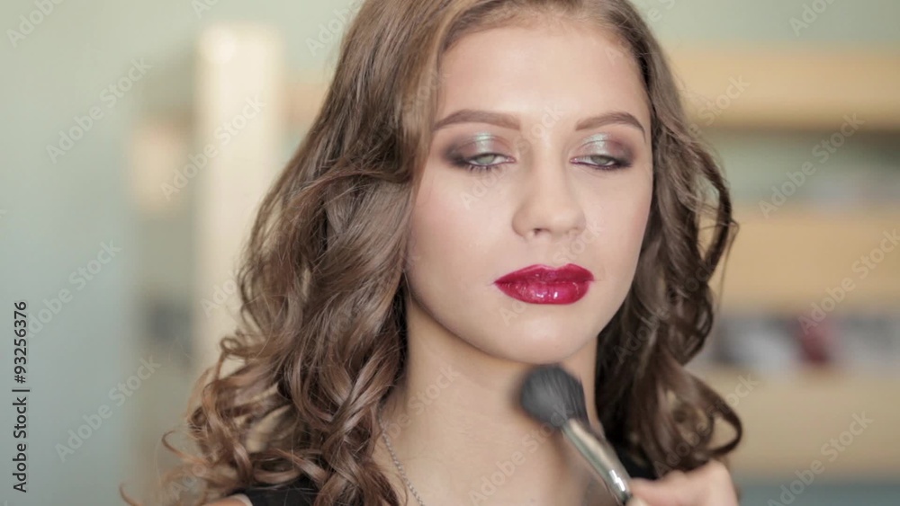 MUA artist doing makeup of a beautiful brunette woman