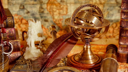 Vintage still life. Vintage magnifying glass lies, pocket watch, old book and astrolabe on an ancient world map in 1565.