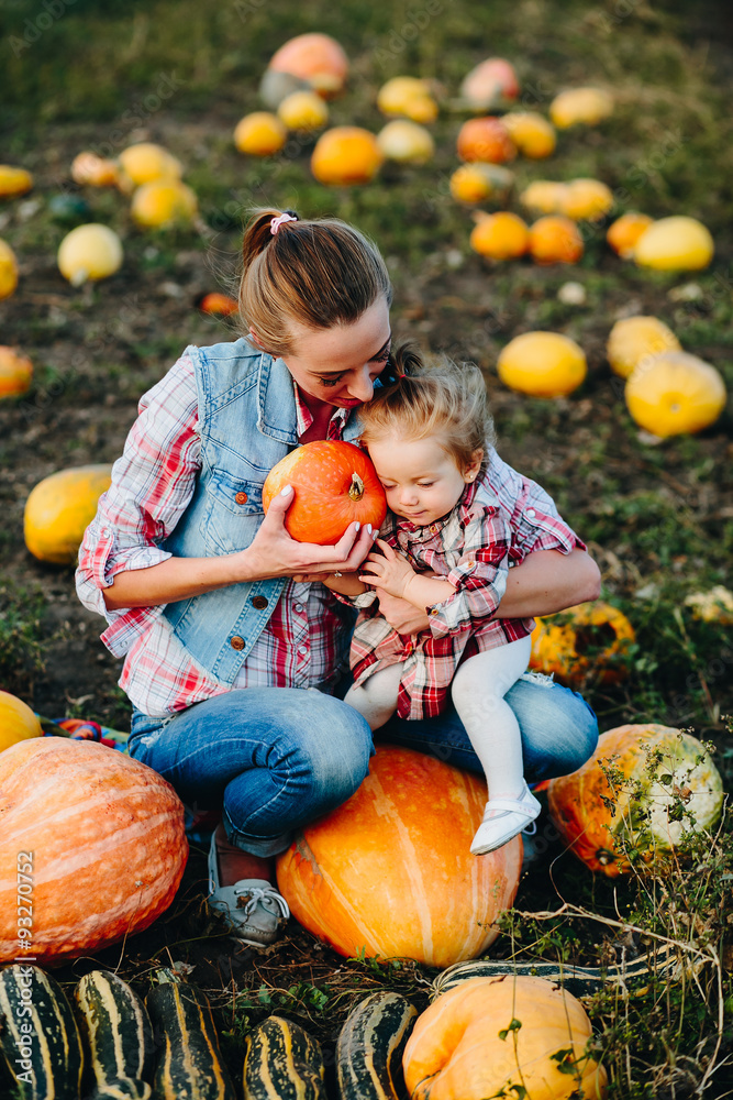 Fototapeta premium Mother and daughter sitting on pumpkins