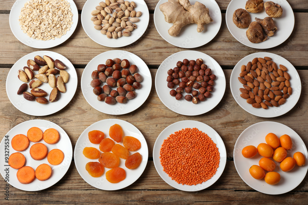 Different products on saucers on wooden table, top view