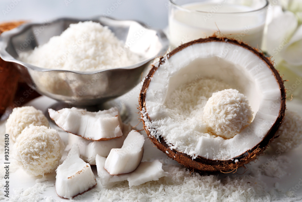 Candies in coconut flakes and fresh coconut on color wooden background Candies in coconut flakes and fresh coconut on color wooden background