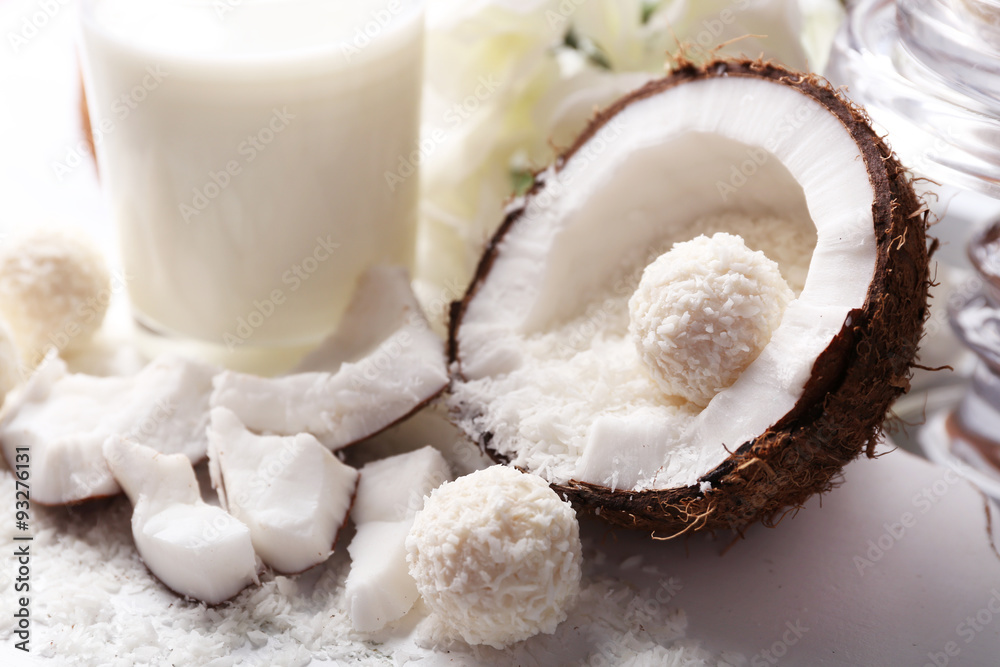Candies in coconut flakes and fresh coconut on color wooden background Candies in coconut flakes and fresh coconut on color wooden background