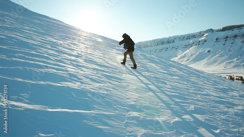 A man trying to climb the mountain on a slippery frozen snow, slips and falls. Time lapse.
