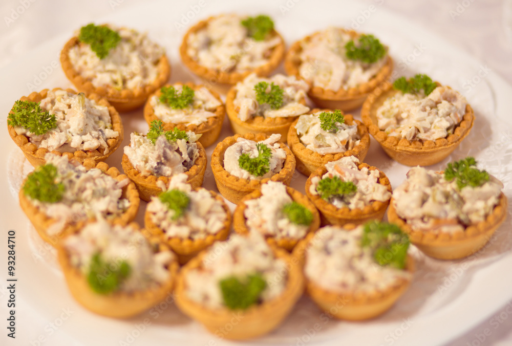 many tartlets with meat salad under mayonnaise and parsley on bu