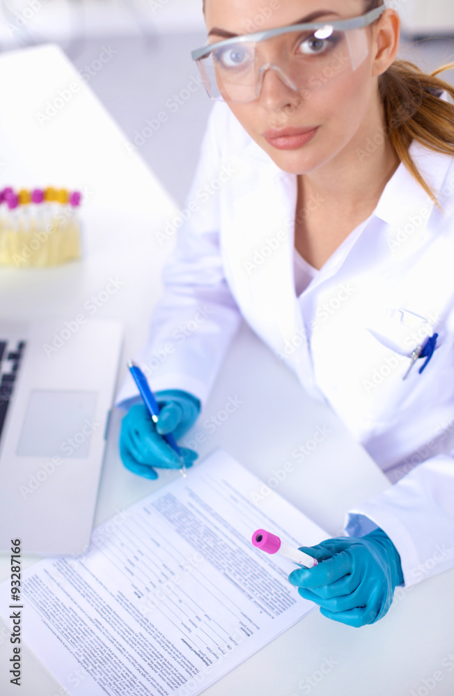Fototapeta premium Woman researcher is surrounded by medical vials and flasks