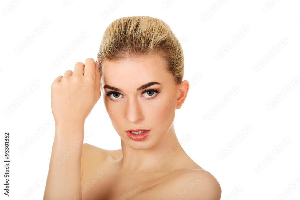 Young topless woman touching her face.