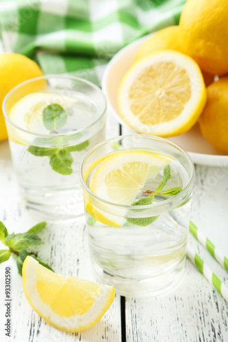 Fresh lemonade with lemon on white wooden background