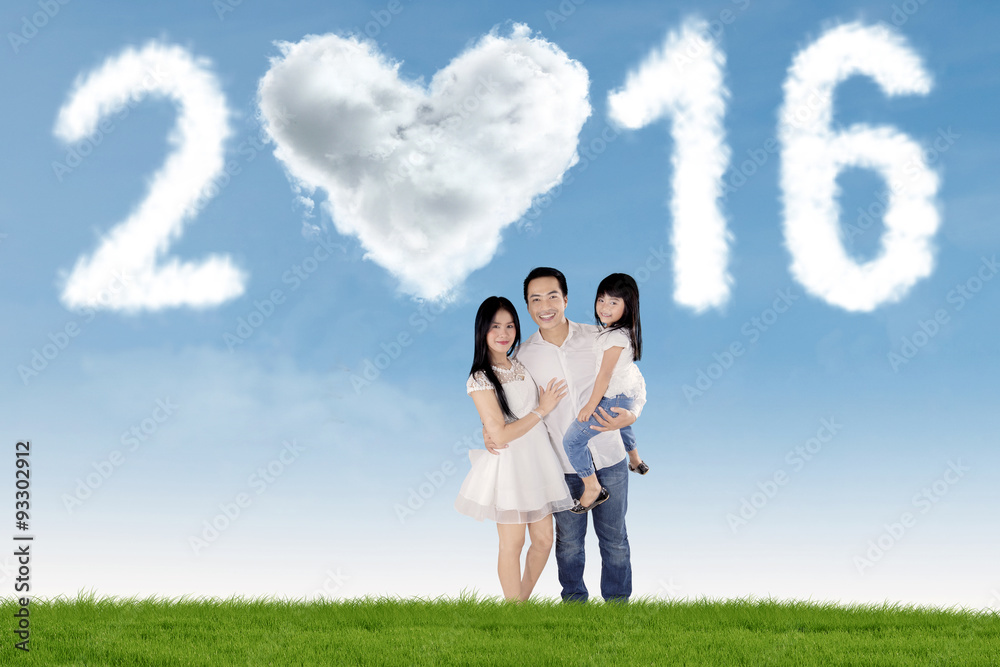 Parents and kid standing at field under numbers 2016