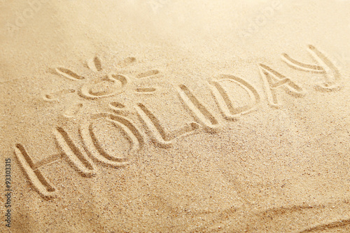 Holiday handwritten in a beach sand