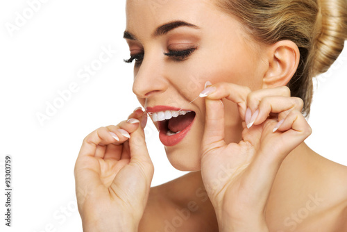 Young woman flossing her teeth.