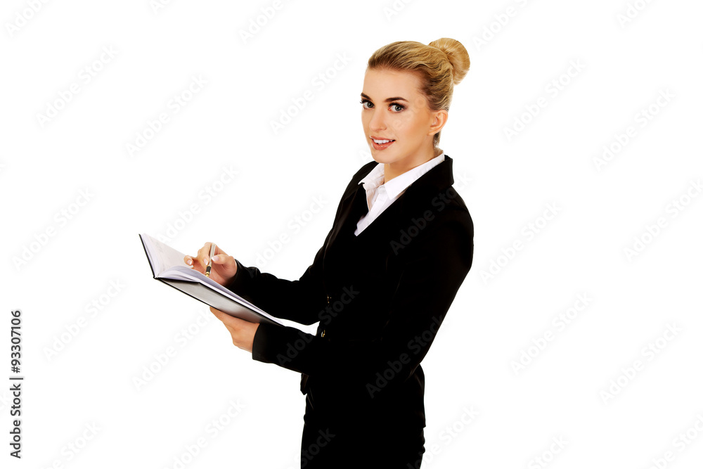 Young businessoman holding notebook and writes something Young businessoman holding notebook and writes something