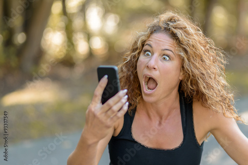 Young woman reacting in horror to a text message