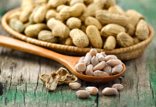  peanuts in the woodspoon and basket on wood photo