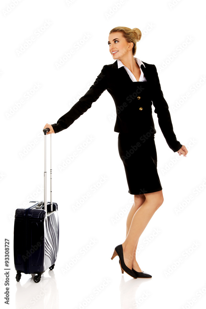 Fototapeta premium Smile businesswoman dragging wheeled suitcase