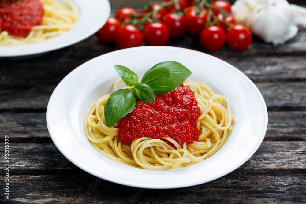 Spaghetti with marinara sauce and basil leaves on top, decorated with vegetables. on wooden table. Spaghetti with marinara sauce and basil leaves on top, decorated with vegetables. on wooden table.