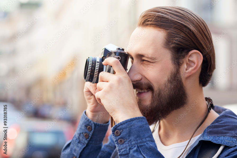 Attractive bearded man is making photos of city