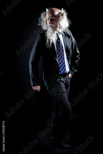 Attractive oldman in classic suit posing on black background