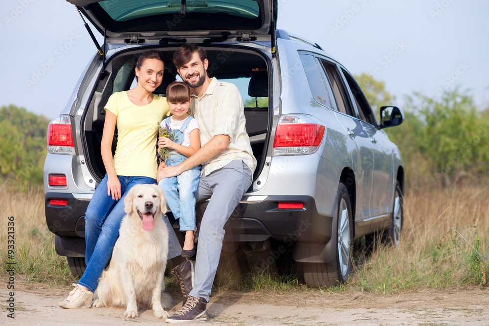 Cheerful married couple and child with puppy near transport Cheerful married couple and child with puppy near transport
