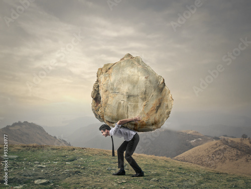 Businessman carrying a big rock