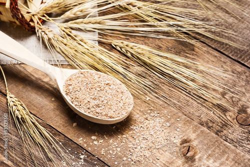 Wheat bran in wooden spoon with wheat ears