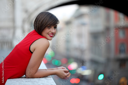 Smiling girl with red dress in urban background photo