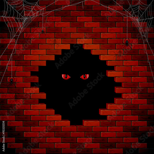 Evil eye in the hole of the brick wall