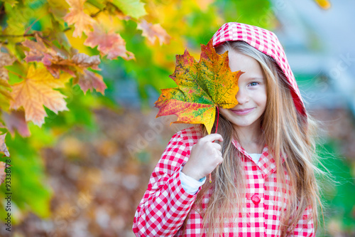 Adorable little girl with colorful leaf at beautiful autumn day photo