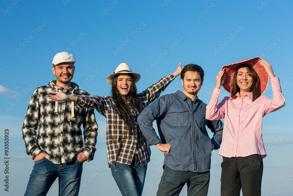 Young Friends Staying and Expressing Positive Emotions Four People Men and Women Together on Blue Sky Background Casual Jeans Style Dress Hands Gesturing Smiling Laughing