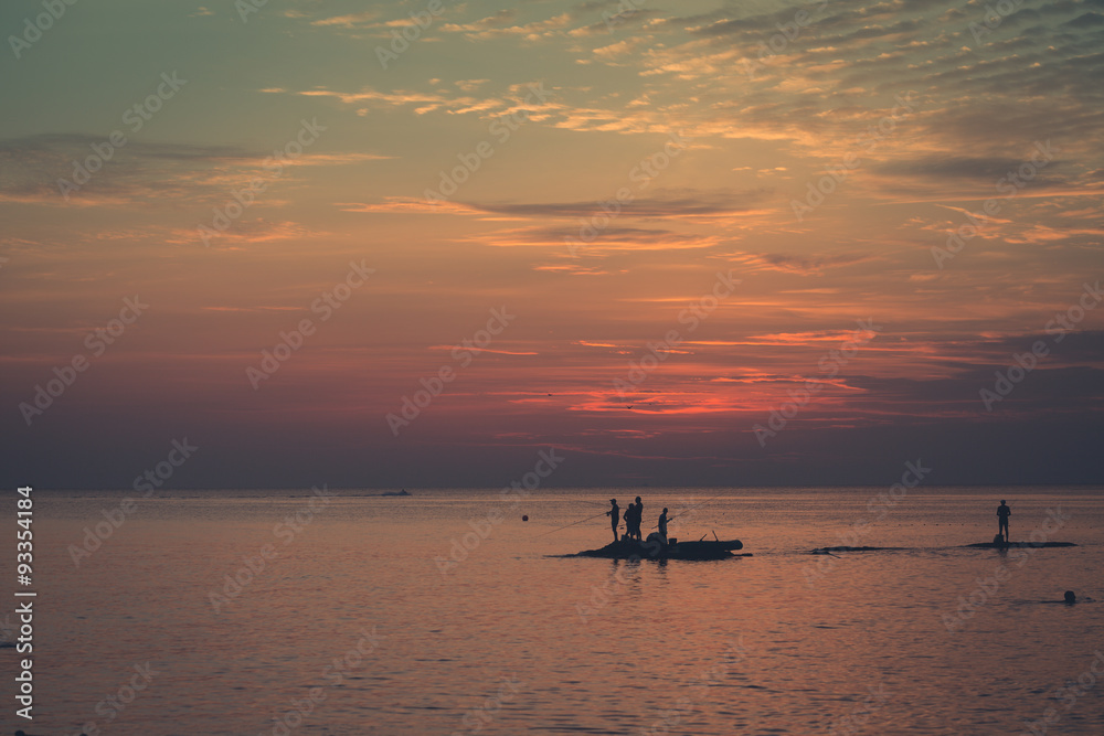 Ocean landscape at sunset. Silhouettes of fishermen.