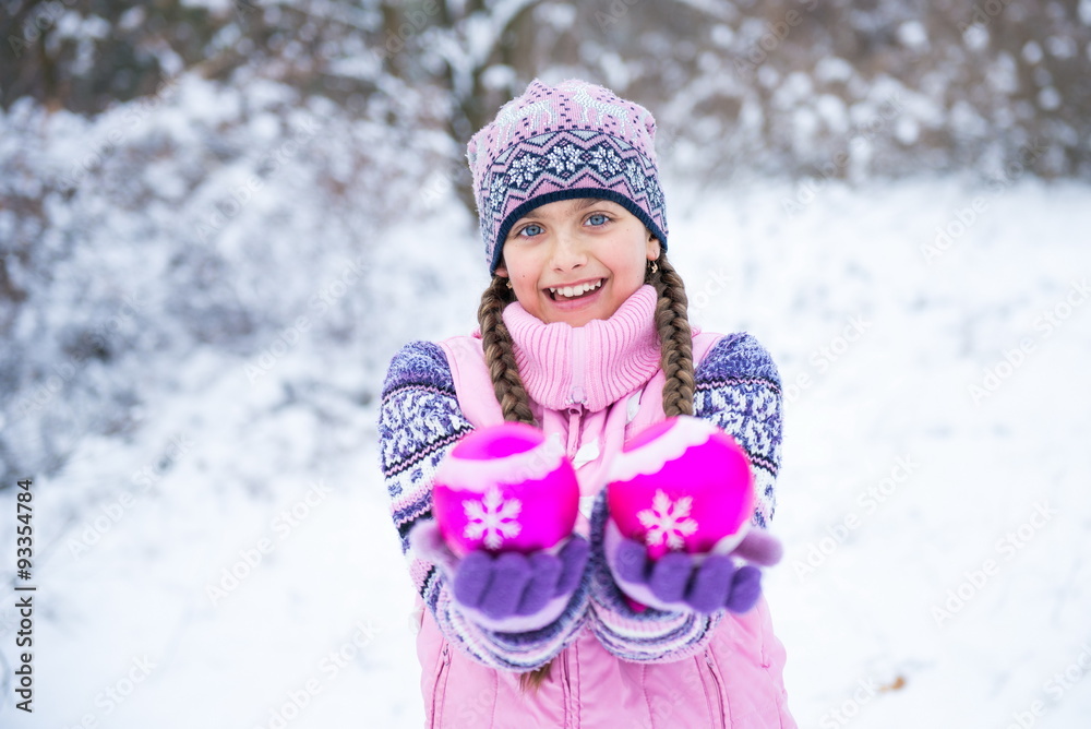 beautiful little girl holding a Christmas ball for Christmas tree decoration. Smiley girl holding 2 pink decorative balls. Before Christmas, girl walking in winter forest beautiful little girl holding a Christmas ball for Christmas tree decoration. Smiley girl holding 2 pink decorative balls. Before Christmas, girl walking in winter forest