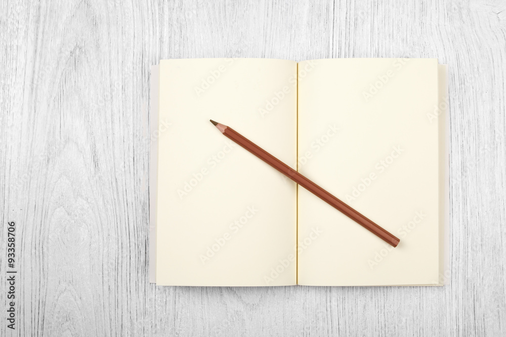 Open brown notebook and a pencil on white wooden table, top view Open brown notebook and a pencil on white wooden table, top view