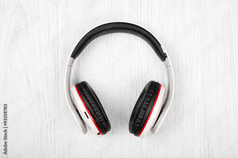 Bluetooth headphones on white wood background Bluetooth headphones on white wood background