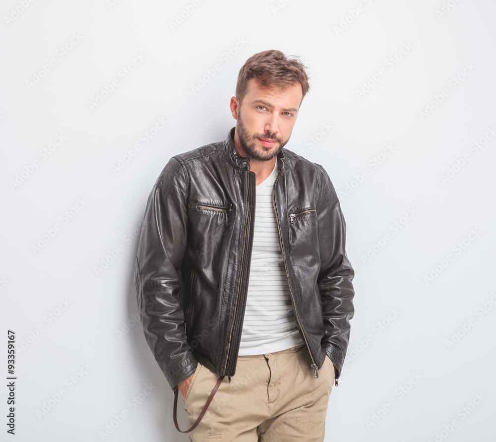 casual young man wearing leather jacket is standing