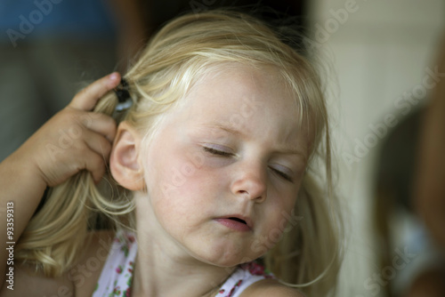 Little girl pulling pony tail behind ear