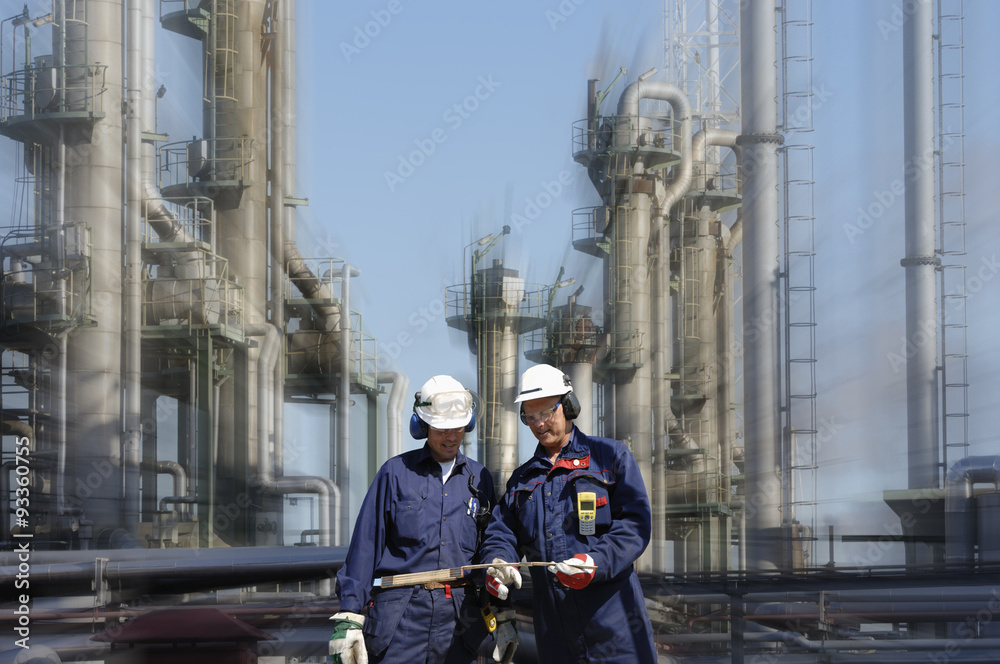 oil and gas industry with two refinery workers in foreground