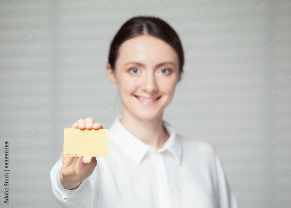 Smiling young woman showing a plastic golden card Smiling young woman showing a plastic golden card