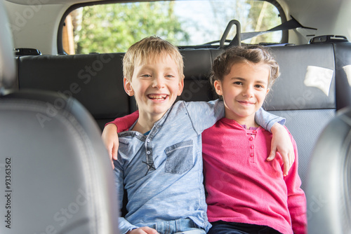 Two ten years old are sitting at the back of a car 