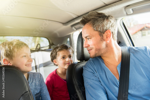 father with beard is talking with his two kids in the car